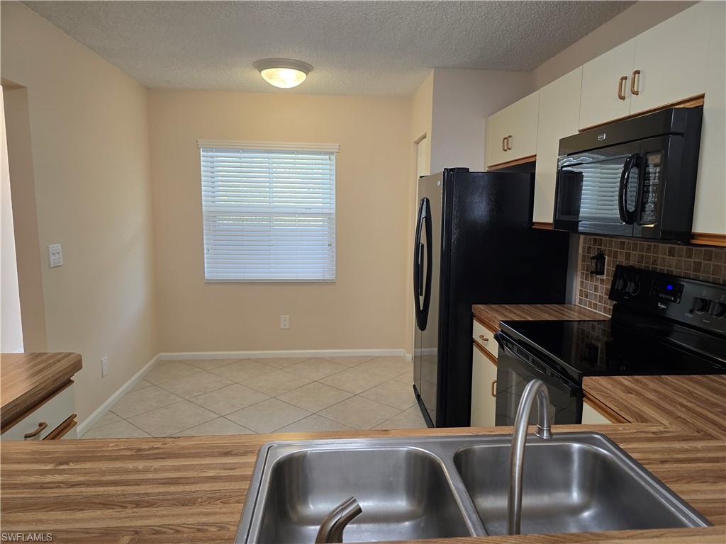 5741 Whitaker Road, Unit D203 Naples, FL 34112 - Photo 7 of 30 a kitchen with a refrigerator and a sink