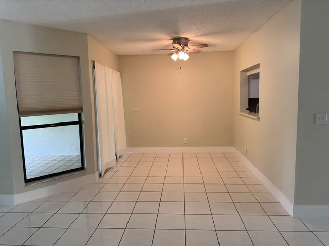 a view of an empty room and chandelier fan