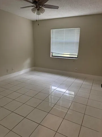 an empty room with windows and ceiling fan