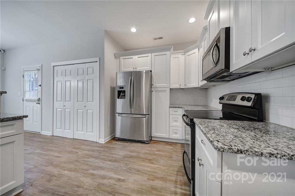 5040 Cheviot Road Charlotte, NC 28269 - Photo 2 of 27 a kitchen with granite countertop a refrigerator and a stove top oven