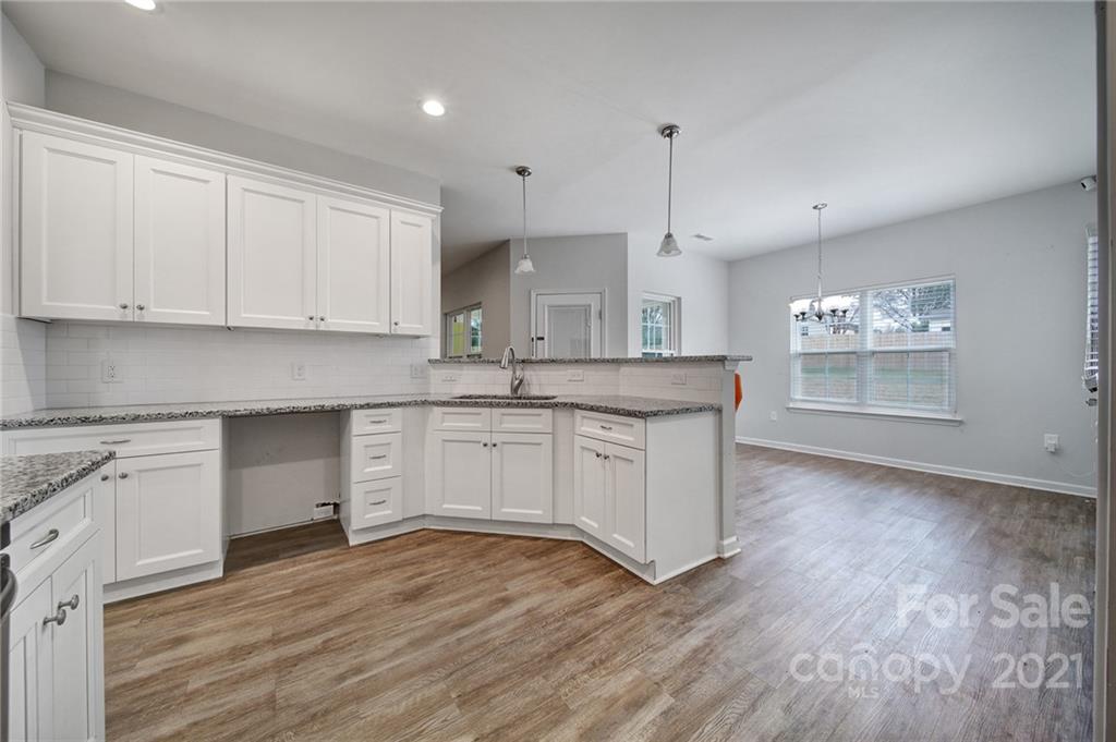 5040 Cheviot Road Charlotte, NC 28269 - Photo 4 of 27 a kitchen with stainless steel appliances granite countertop a sink a stove and white cabinets with wooden floor