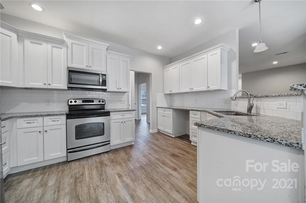 5040 Cheviot Road Charlotte, NC 28269 - Photo 5 of 27 a kitchen with stainless steel appliances granite countertop a sink a stove a refrigerator and white cabinets