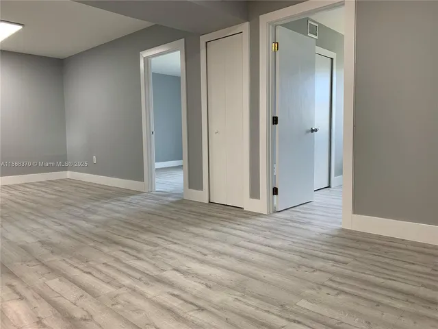 an empty room with wooden floor and mirror