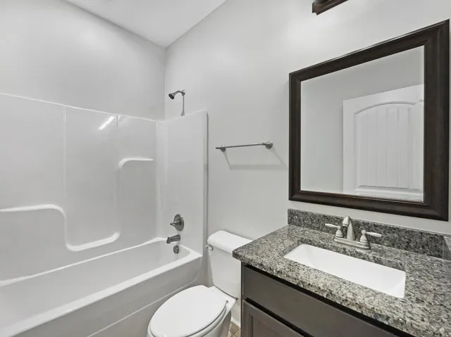 a bathroom with a granite countertop tub sink toilet and mirror