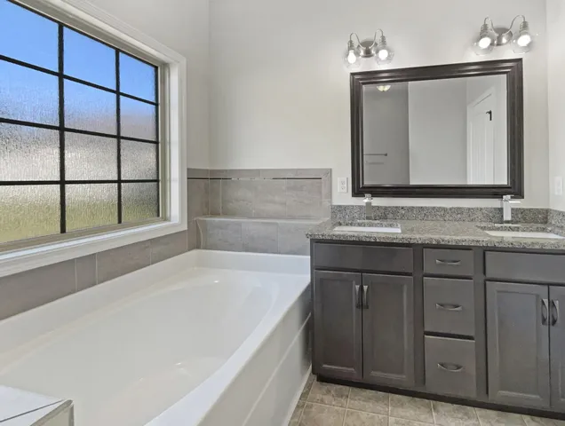 a bathroom with a granite countertop sink and a bathtub