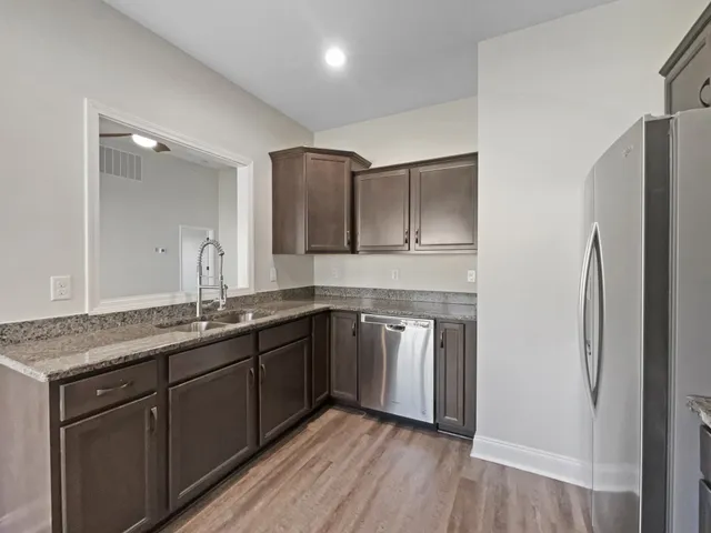 a kitchen with stainless steel appliances granite countertop a refrigerator a sink and wooden cabinets