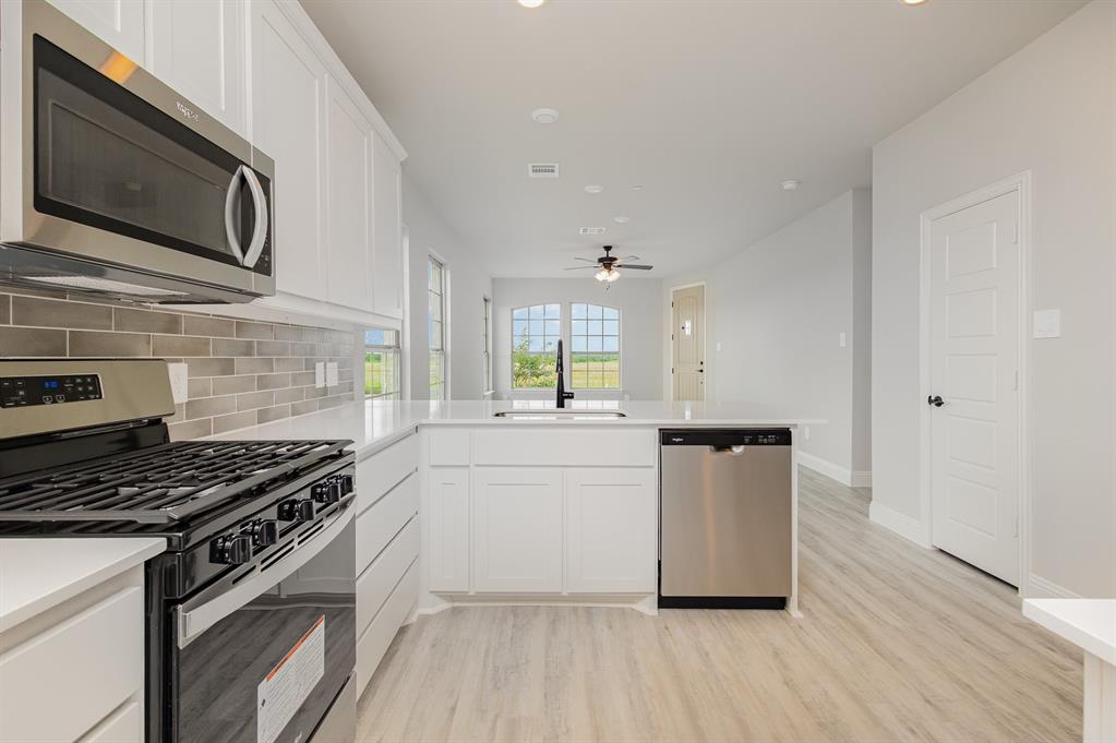 3613 Geoffrey Trail Rowlett, TX 75088 - Photo 5 of 13 Kitchen with appliances with stainless steel finishes, white cabinetry, a peninsula, light wood-type flooring, and recessed lighting