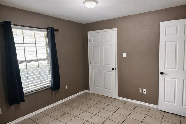 a view of an empty room with window and cabinet