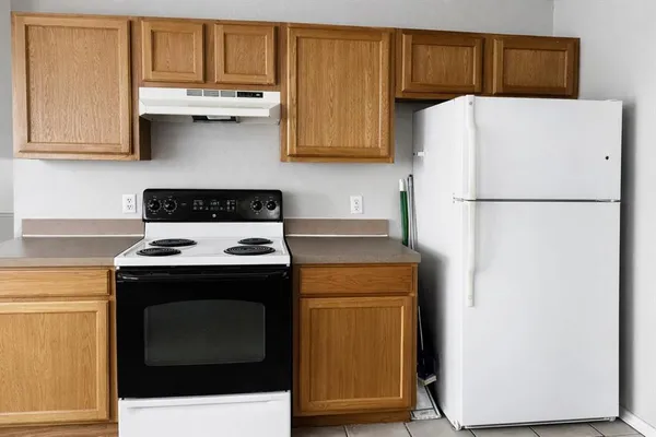 a white refrigerator freezer sitting inside of a kitchen with stainless steel appliances wooden floor