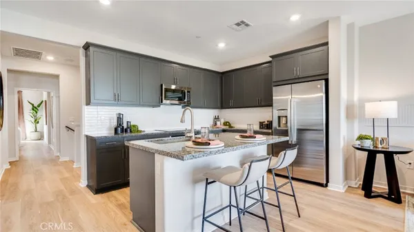 a kitchen with stainless steel appliances kitchen island granite countertop a refrigerator a stove a sink and a dining table with wooden floor