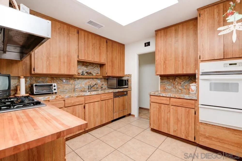 4470 Monahan Road La Mesa, CA 91941 - Photo 8 of 26 a kitchen with stainless steel appliances granite countertop wooden cabinets a stove a sink and a refrigerator