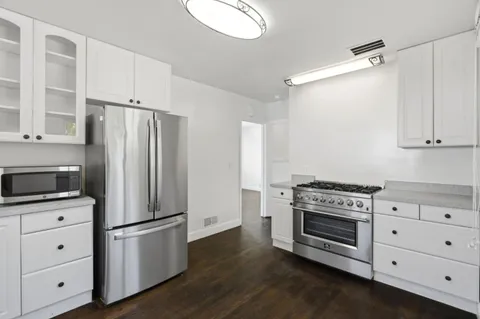 a kitchen with cabinets appliances and wooden floor