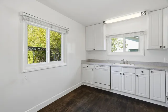 a kitchen with granite countertop white cabinets and a window
