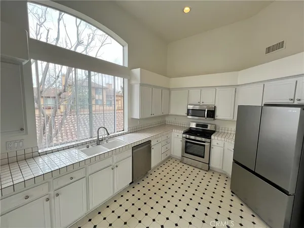 a kitchen with granite countertop a refrigerator a sink a stove a washer dryer and a dining table