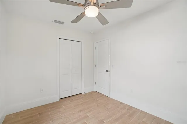 a view of an empty room and chandelier fan