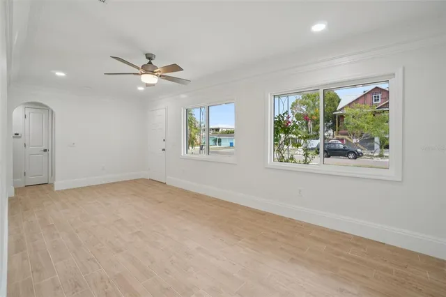 an empty room with windows and ceiling fan