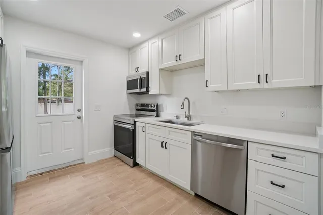 a kitchen with cabinets appliances a sink and a window