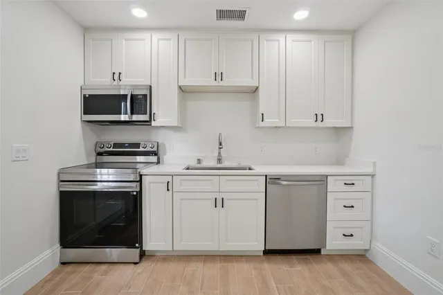 a kitchen with stainless steel appliances granite countertop a stove a sink and a microwave