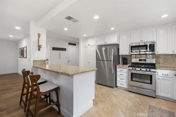 a kitchen with stainless steel appliances kitchen island a table chairs refrigerator and microwave