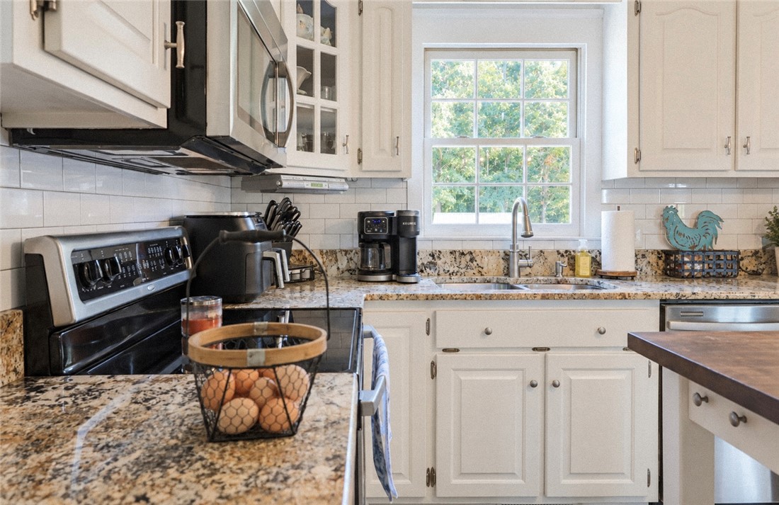 2420 Rainey Road Starr, SC 29684 - Photo 12 of 36 Polished granite countertops complement classic white cabinetry in this workspace centered around a window view.