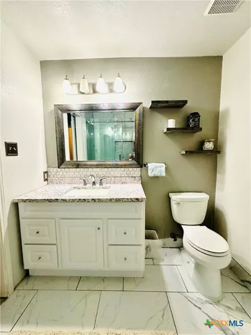 a bathroom with a granite countertop toilet sink and mirror
