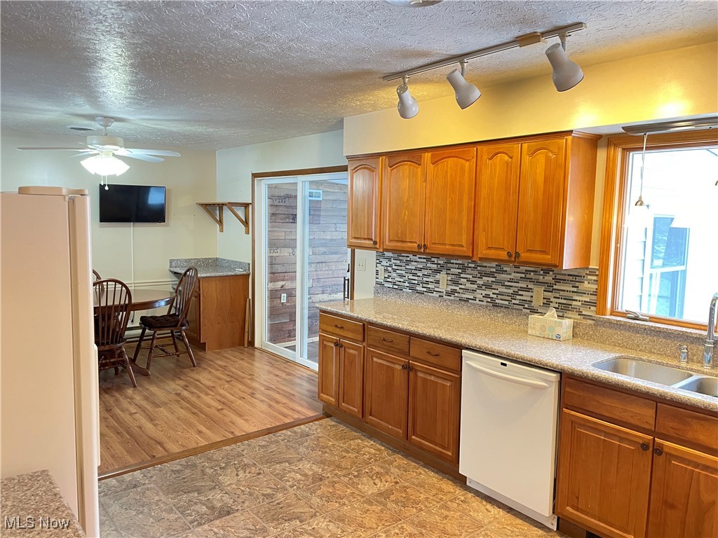 1381 Robb Road Conneaut, OH 44030 - Photo 15 of 50 Kitchen featuring white appliances, brown cabinetry, a textured ceiling, ceiling fan, and light stone counters