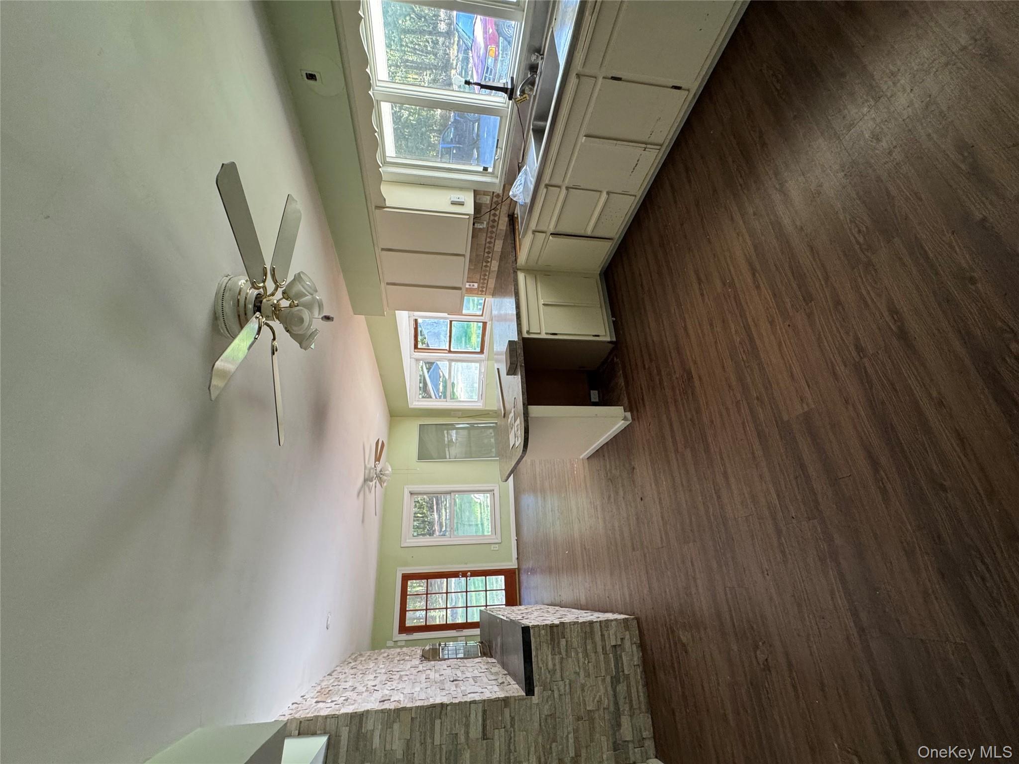 33 Mount Sinai-Coram Road Coram, NY 11727 - Photo 5 of 5 Kitchen with a peninsula, dark wood-style floors, white cabinetry, backsplash, and open floor plan