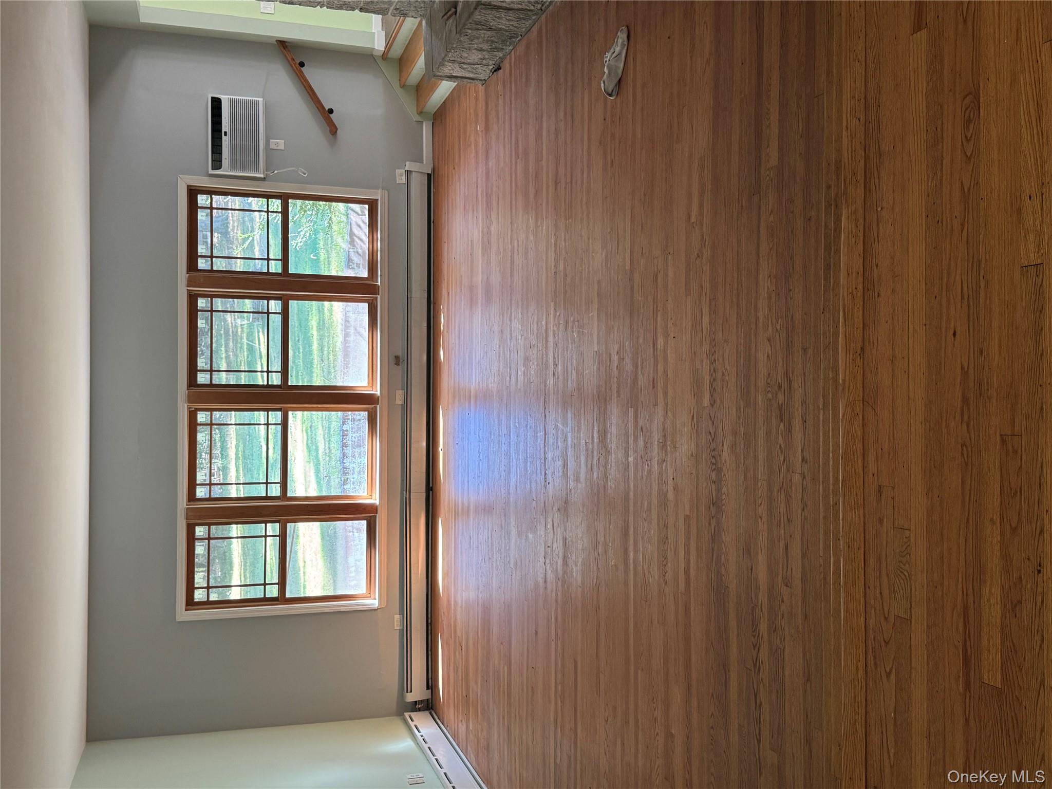 33 Mount Sinai-Coram Road Coram, NY 11727 - Photo 3 of 5 Unfurnished room featuring hardwood / wood-style flooring, baseboard heating, and stairway