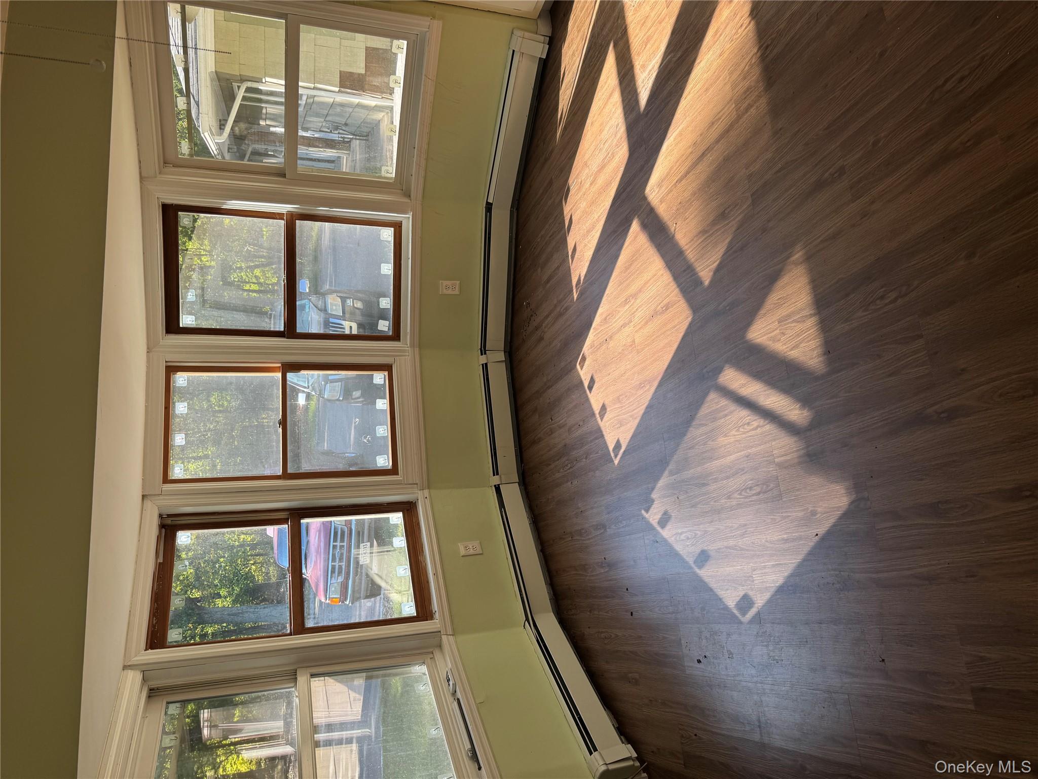 33 Mount Sinai-Coram Road Coram, NY 11727 - Photo 4 of 5 Spare room with healthy amount of natural light, a baseboard heating unit, and dark wood-style flooring