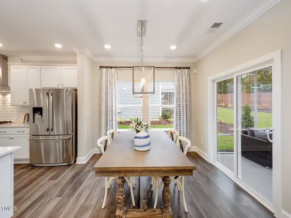 a kitchen with stainless steel appliances a dining table chairs and wooden floor