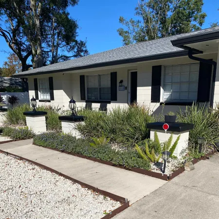 a front view of a house with a yard and potted plants