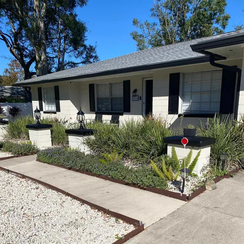 a front view of a house with a yard and potted plants