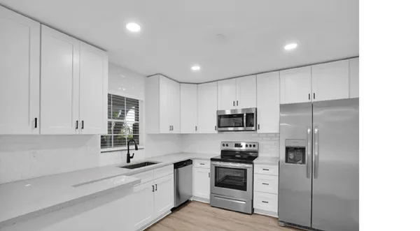 a kitchen with stainless steel appliances granite countertop a refrigerator sink and stove