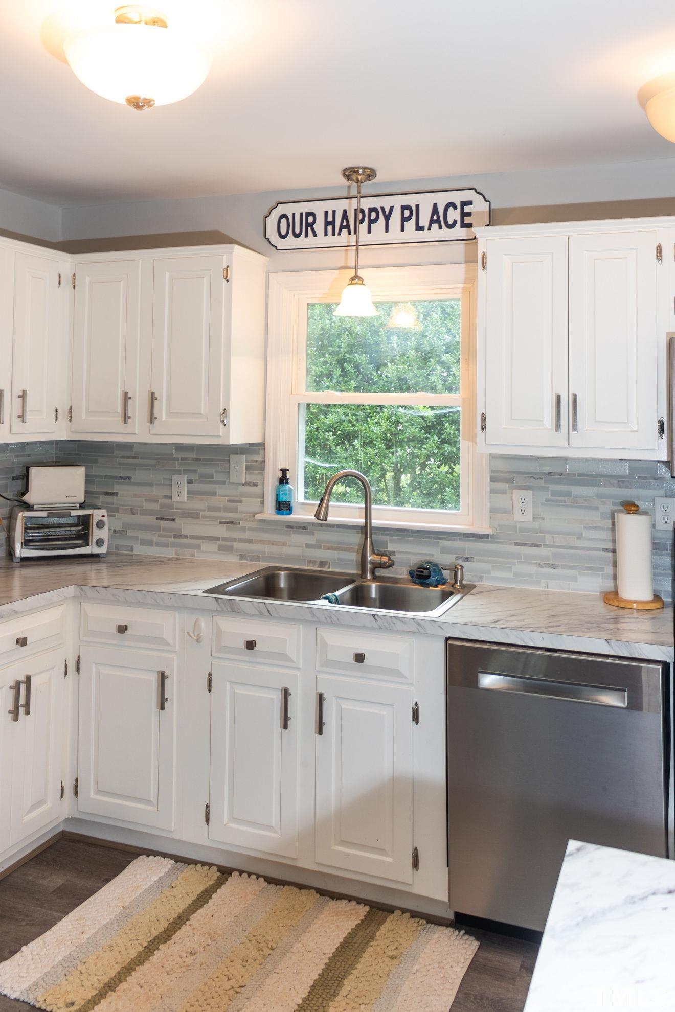 70 Waters Edge Loop Henderson, NC 27537 - Photo 15 of 49 a kitchen with granite countertop white cabinets white appliances and a large window