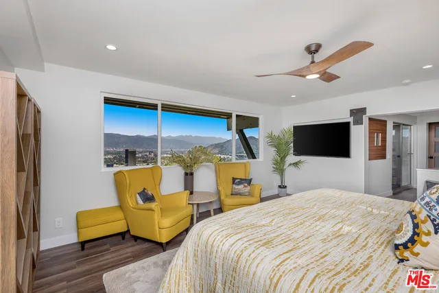 a bedroom with a bed a flat screen tv and balcony