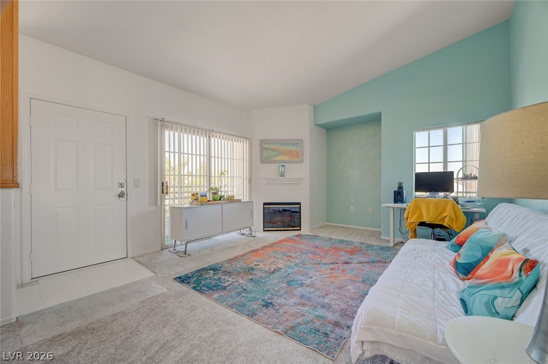 3318 North Decatur Boulevard, Unit 2072 Las Vegas, NV 89130 - Photo 7 of 50 A well-lit living area features a corner fireplace and a balcony for outdoor access.