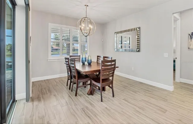 a kitchen with kitchen island a stove a refrigerator a sink and a dining table with wooden floor