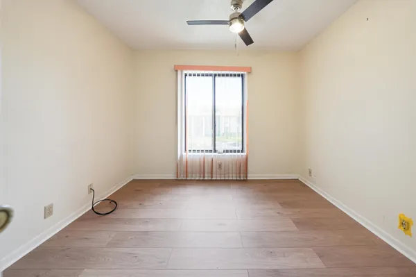 an empty room with wooden floor fan and windows