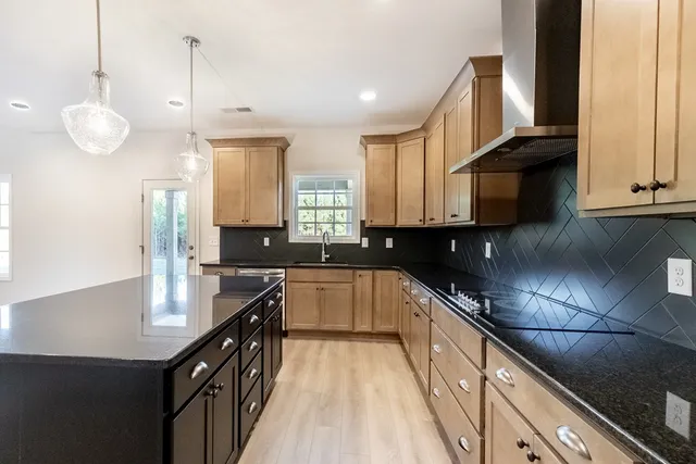 a kitchen with stainless steel appliances granite countertop a sink a stove and a wooden floors