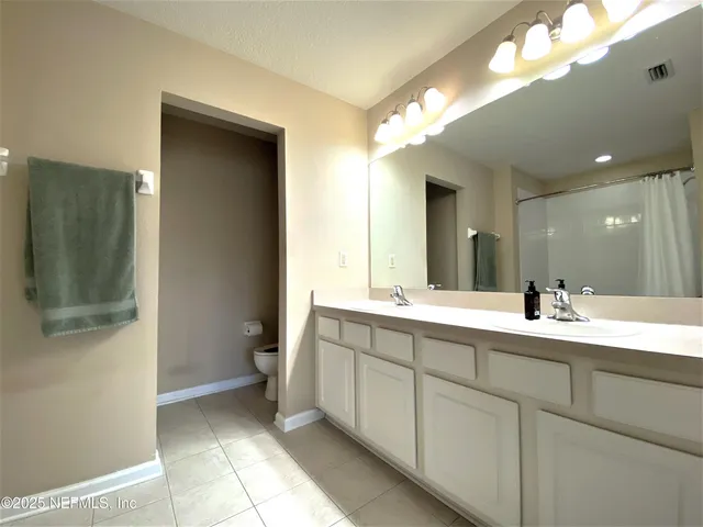a spacious bathroom with a double vanity sink a toilet and a mirror