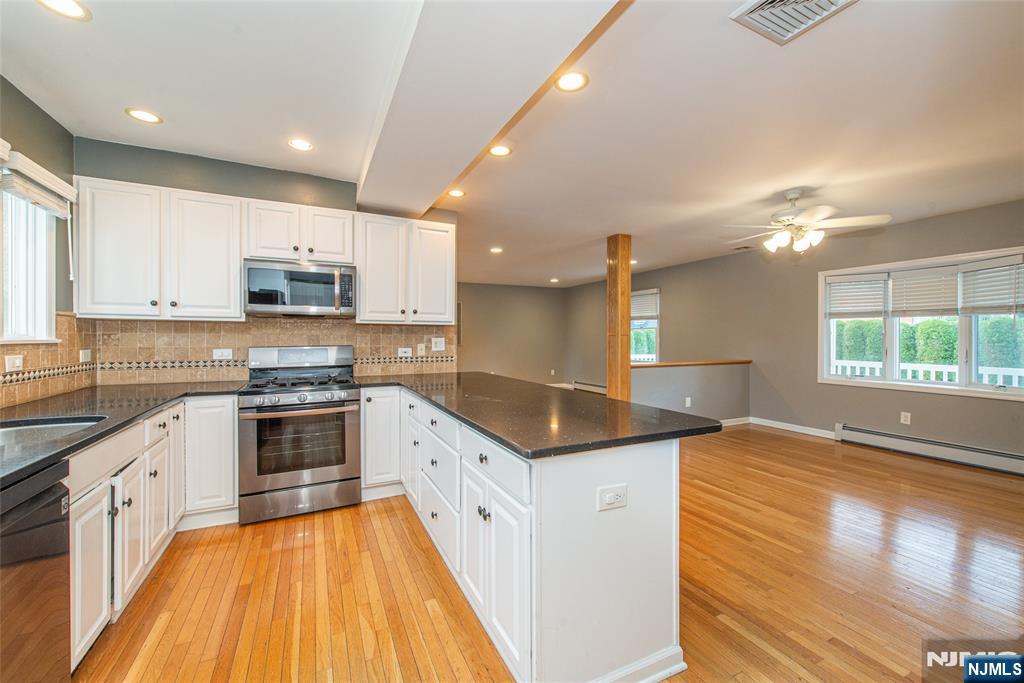73 Grove Street Clifton, NJ 07013 - Photo 10 of 49 a kitchen with kitchen island granite countertop a stove a sink and white cabinets with wooden floor