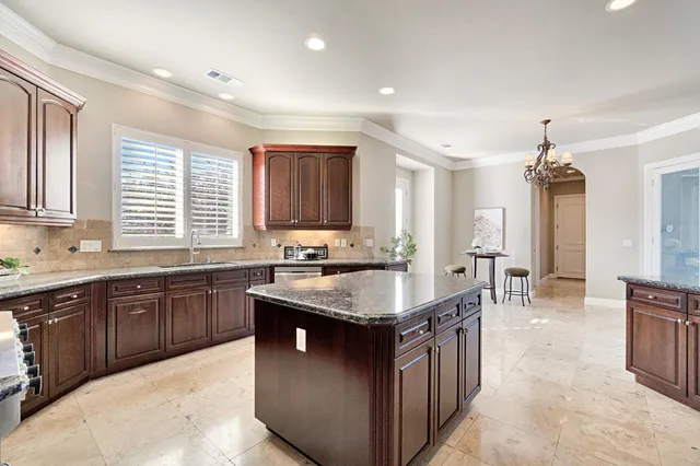 a large living room with stainless steel appliances kitchen island granite countertop furniture a rug a fireplace and a window