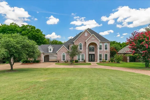 a front view of a house with a garden and trees