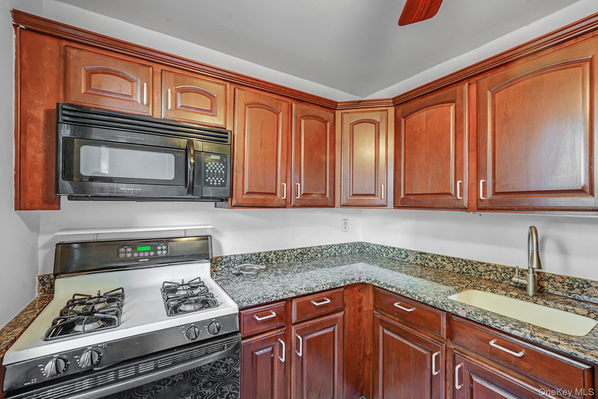 67-50 Thornton Place, Unit 4U Queens, NY 11375 - Photo 12 of 19 Kitchen featuring range with gas cooktop, black microwave, dark stone countertops, and ceiling fan
