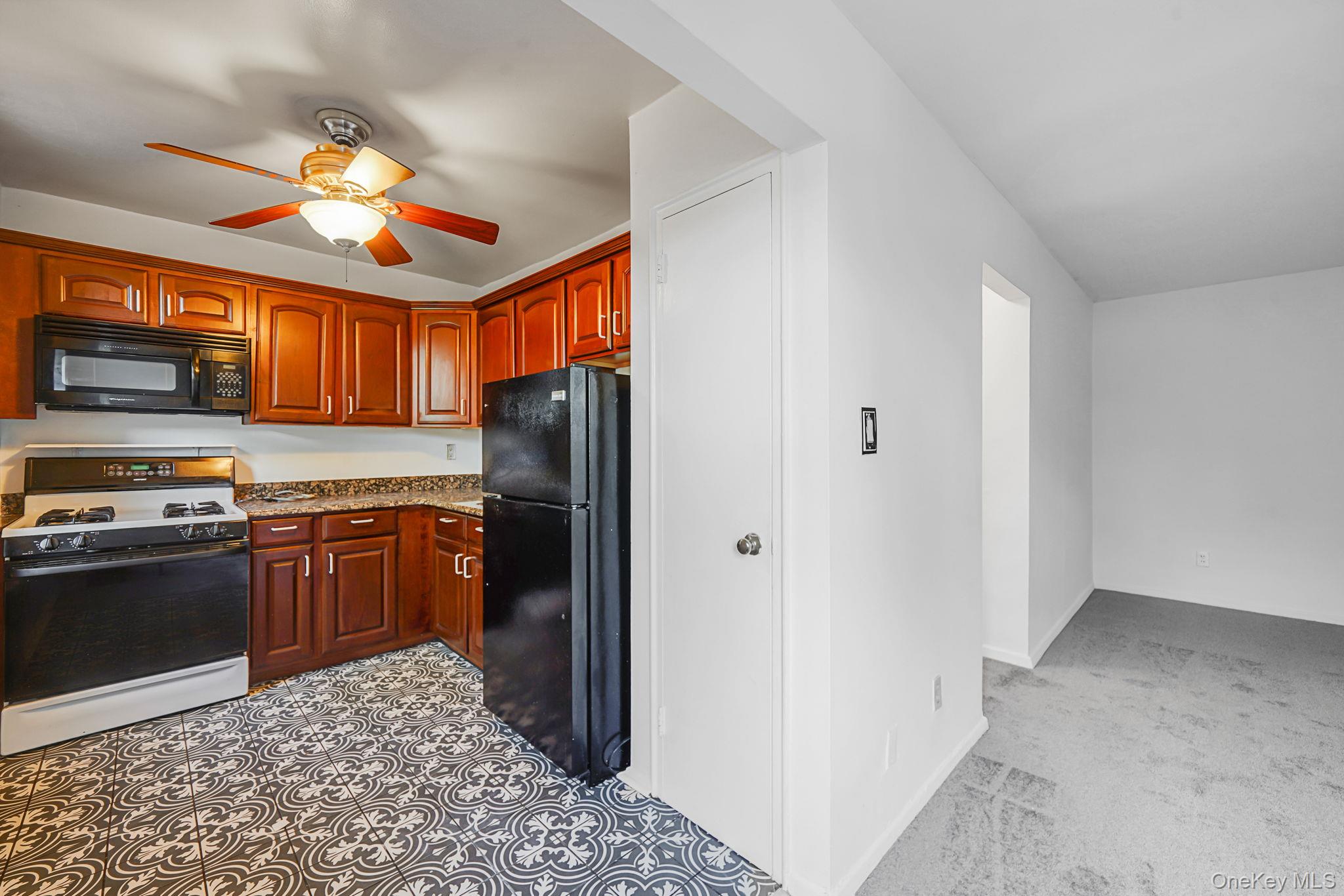 67-50 Thornton Place, Unit 4U Queens, NY 11375 - Photo 10 of 19 Kitchen featuring black appliances, light stone countertops, ceiling fan, and light carpet