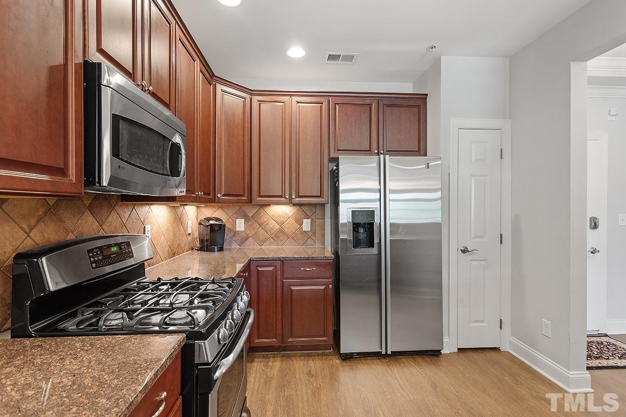 10421 Rosegate Court, Unit 5 Raleigh, NC 27617 - Photo 11 of 35 a kitchen with granite countertop wooden cabinets stainless steel appliances and a wooden floor