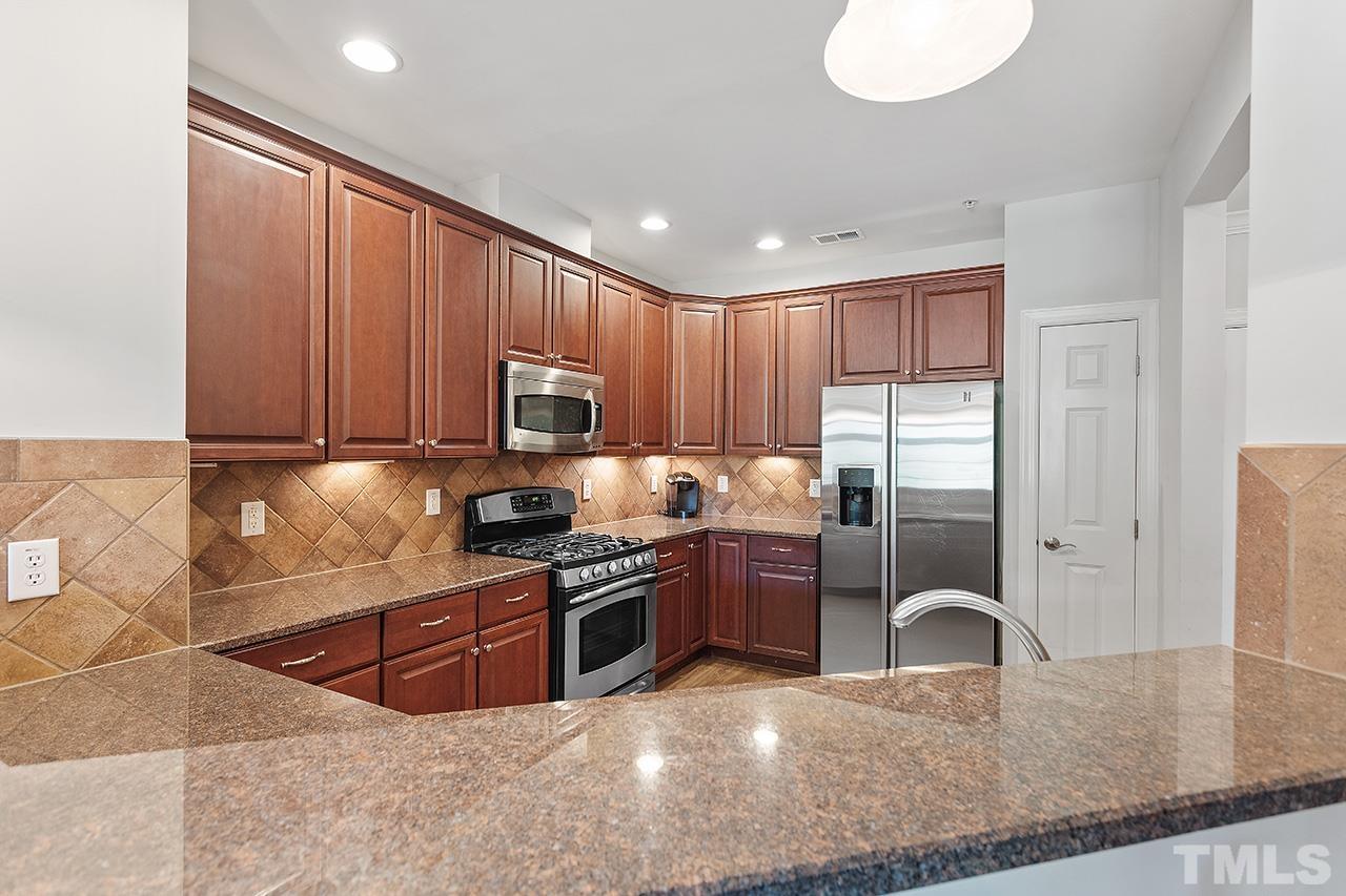 10421 Rosegate Court, Unit 5 Raleigh, NC 27617 - Photo 13 of 35 a kitchen with stainless steel appliances granite countertop a stove top oven a sink dishwasher a dining table and chairs