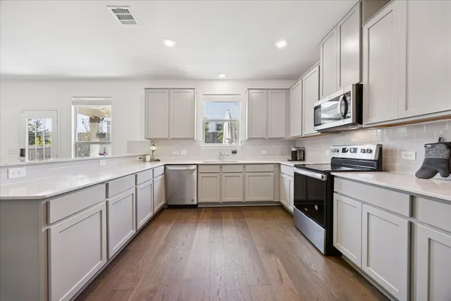 a kitchen with stainless steel appliances a sink cabinets and wooden floor