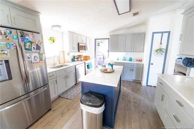 a kitchen with stainless steel appliances a stove a refrigerator a sink a counter space and wooden floor