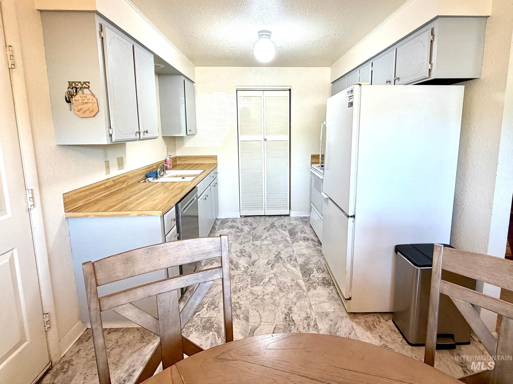 3920 North Maple Grove Road Boise, ID 83704 - Photo 15 of 29 Kitchen featuring wood-finish countertops, white appliances, and light gray cabinetry